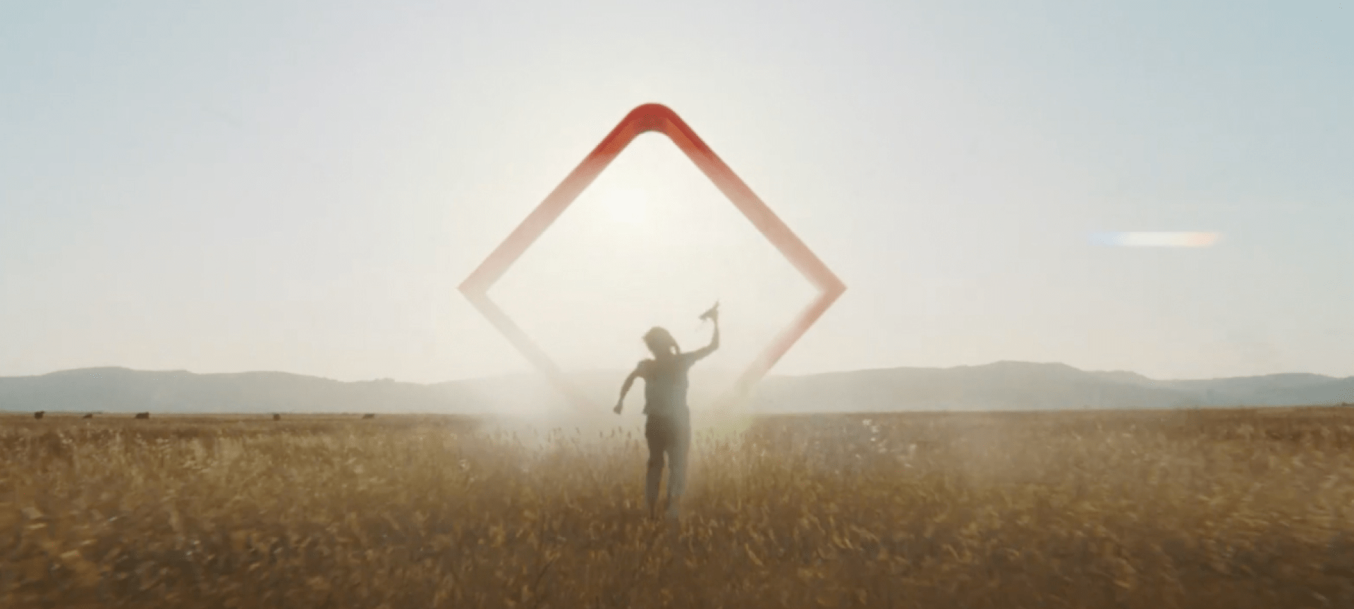 A person walking through a field toward a glowing, red, geometric CIBC logo