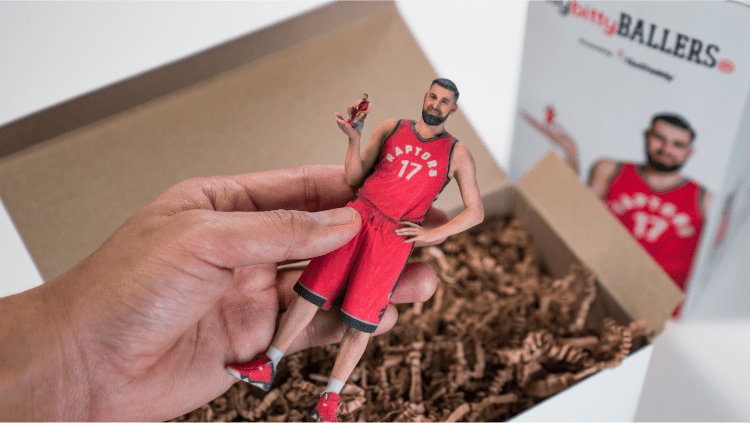 A hand holding a small figurine of Jonas Valančiūnas, packaged as part of the Itty Bitty Ballers collection