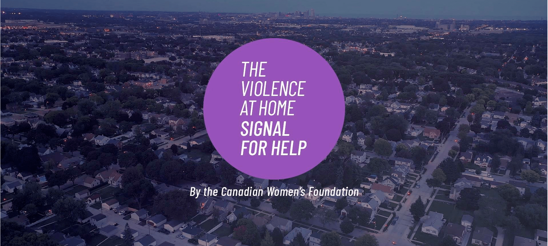 An aerial view of a suburban neighborhood at dusk, with the words 'The Violence at Home Signal for Help' displayed in a purple circle in the center, by the Canadian Women's Foundation.