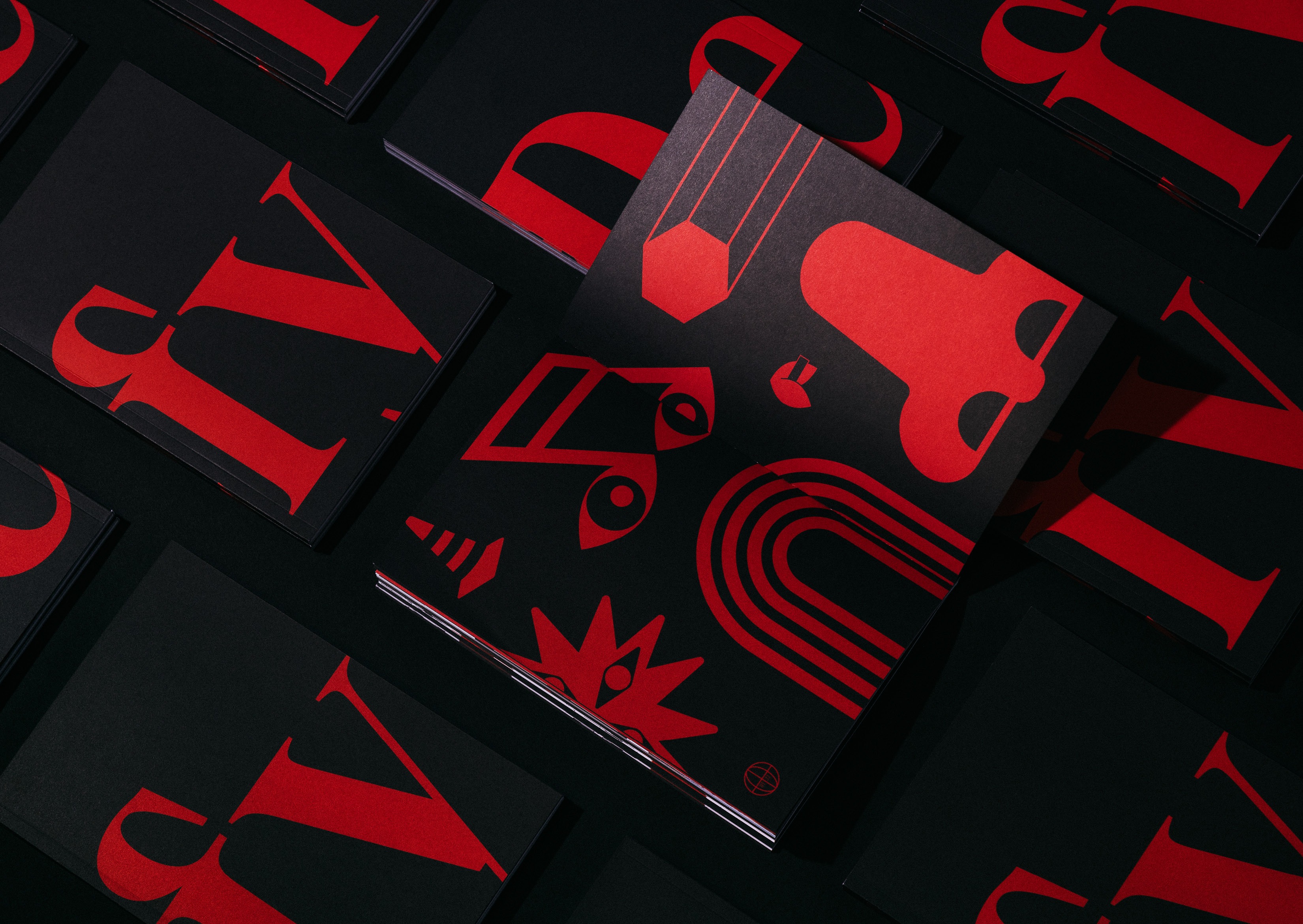 Red and black printed notebooks featuring abstract icons and bold 'Defy' text in a striking minimalist design