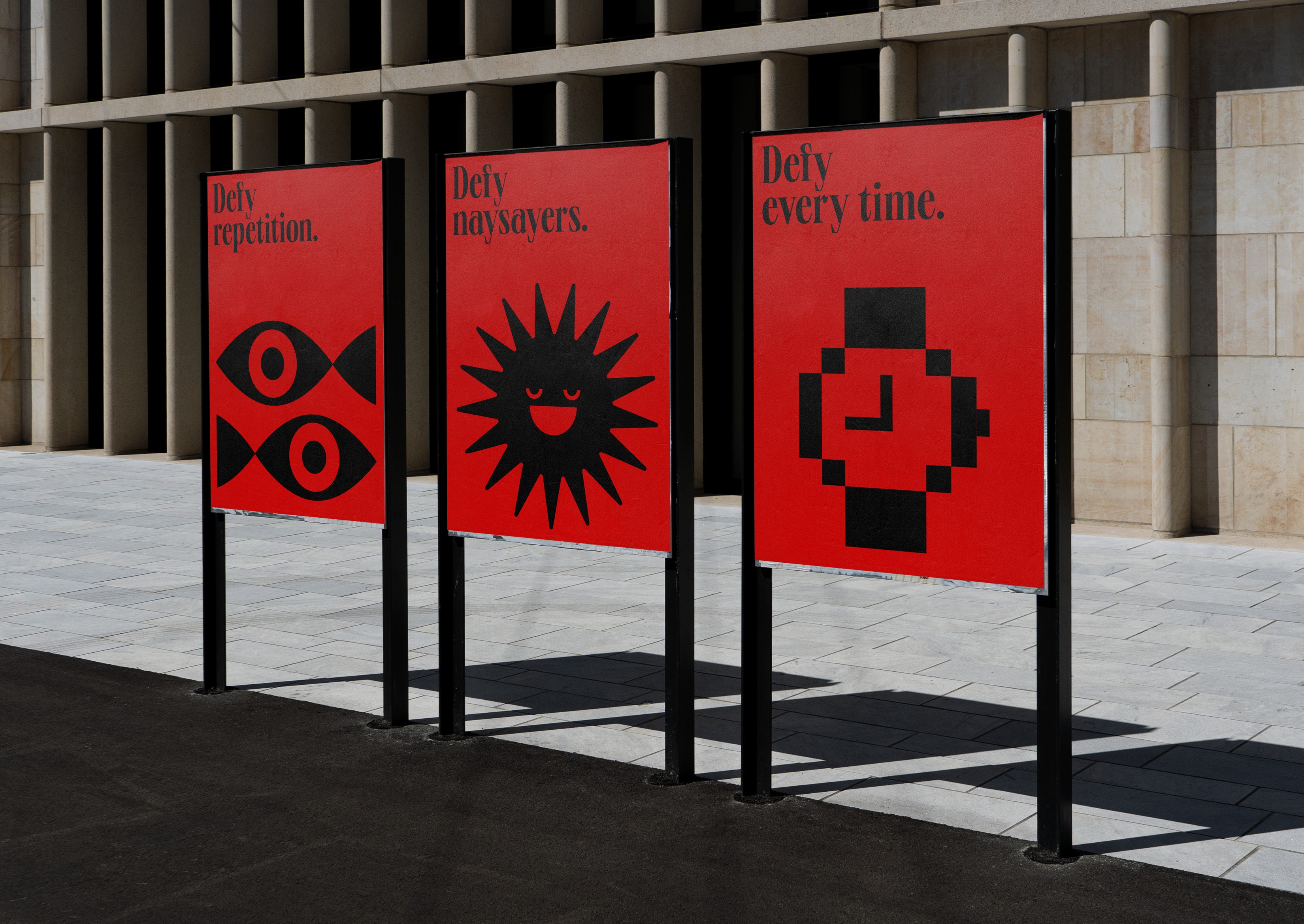 Three red posters with bold black icons and slogans: 'Defy repetition,' 'Defy naysayers,' and 'Defy every time