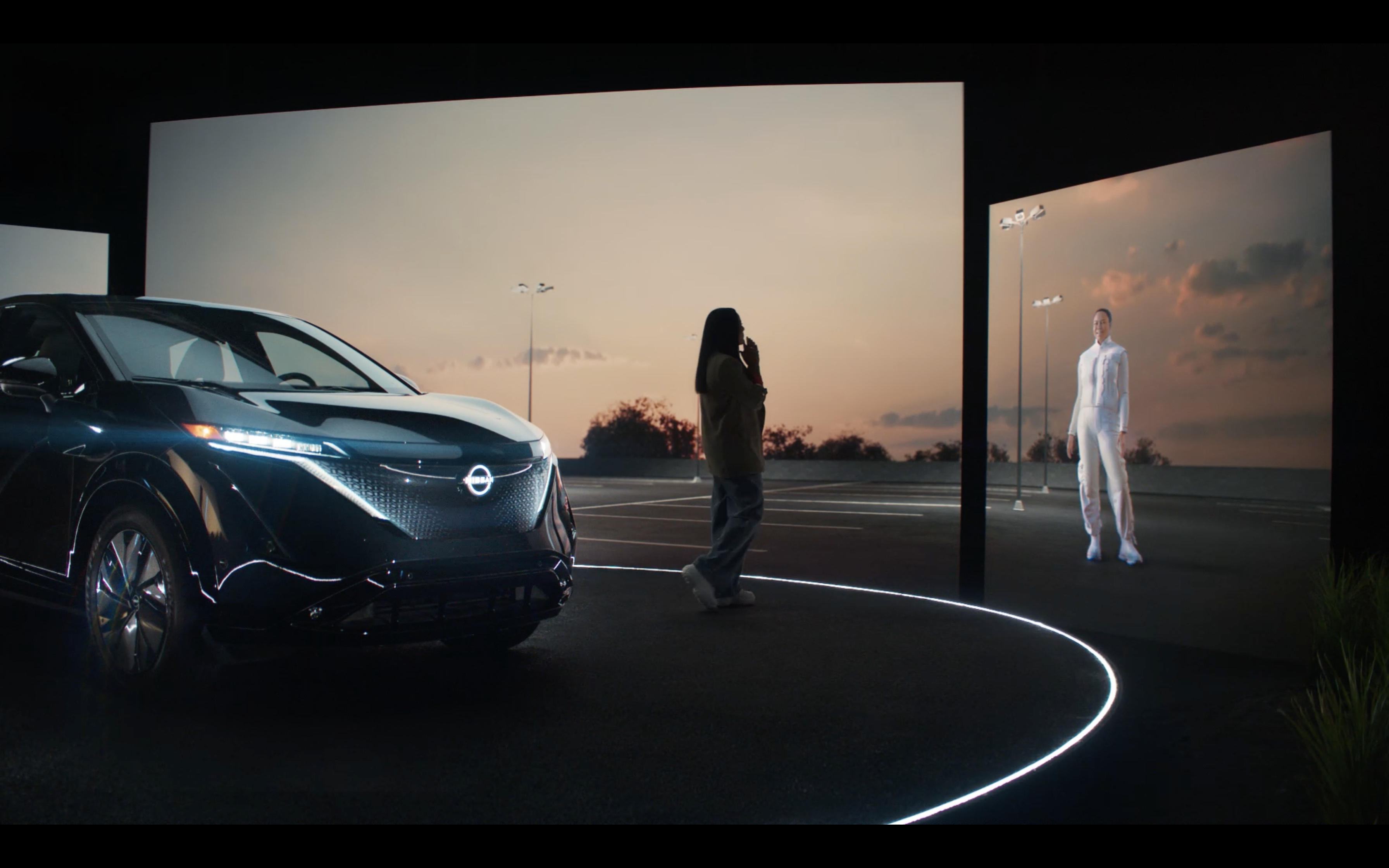 A woman stands in front of a Nissan ARIYA during an AI-led test drive experience featuring her own digital avatar as a personalized virtual guide.