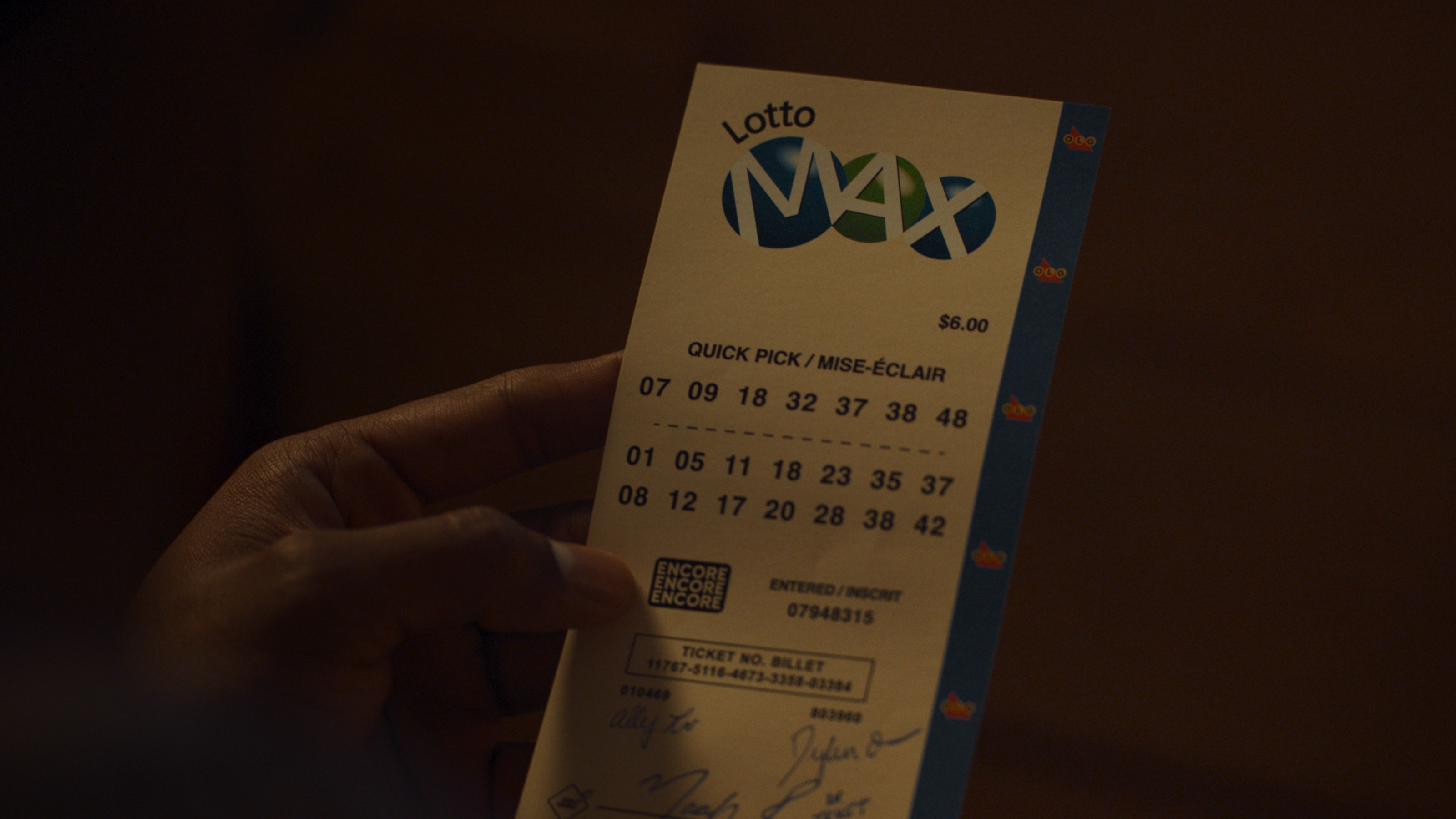 A hand holding a Lotto Max ticket, showing selected numbers for a quick pick draw.