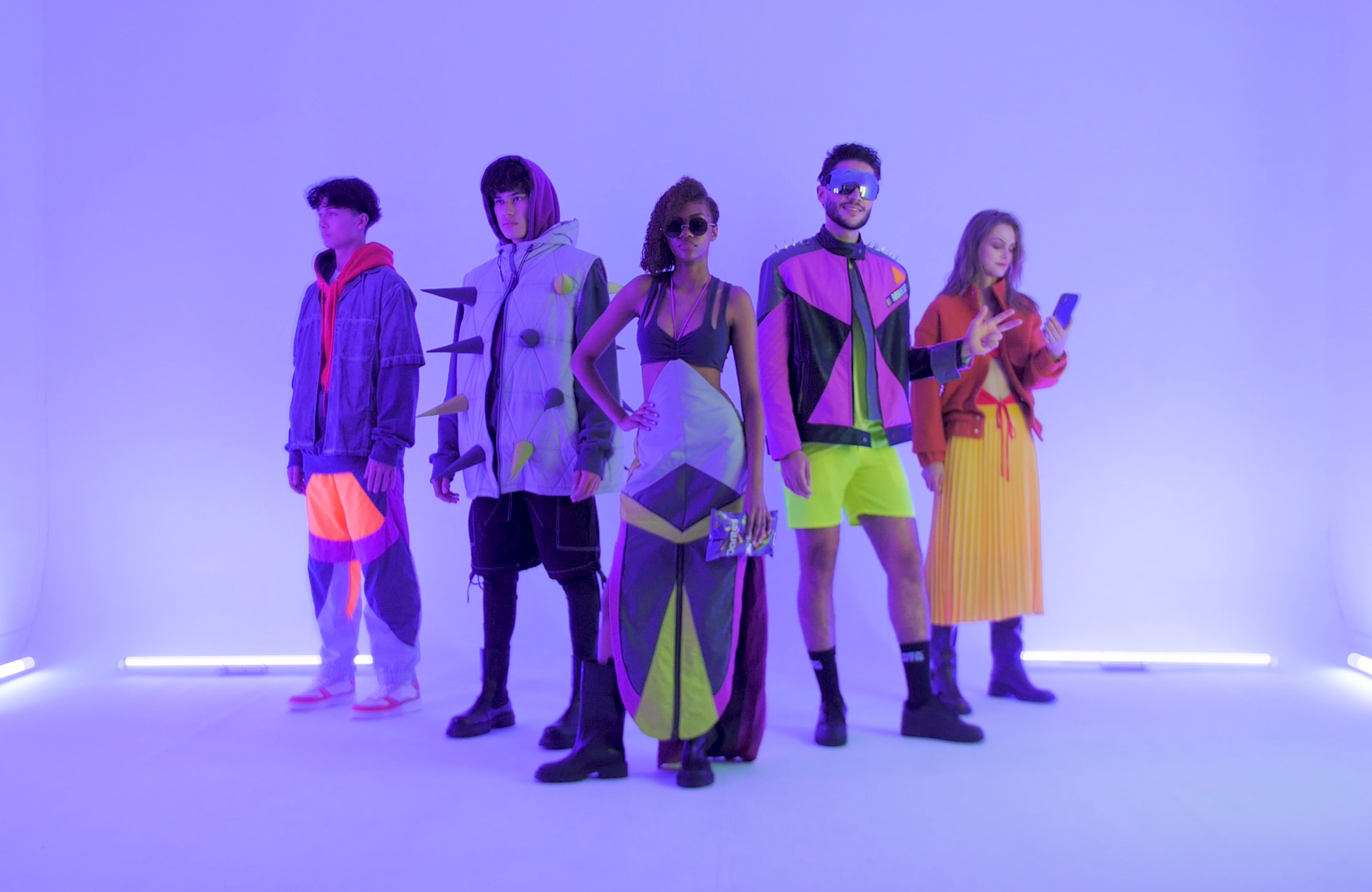 : Five models showcase the real-world versions of the futuristic outfits in a neon-lit room, matching the NPC designs from the campaign.